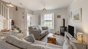 A living room with a grey sofa, a wooden coffee table, a TV, and a fireplace. - 2 Bed in Camber (oc-r31753) (Camber)
