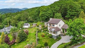 Et boligområde med huse omgivet af frodig vegetation og bakker.