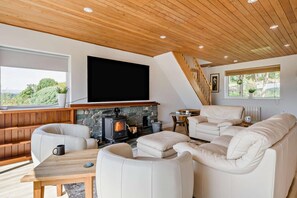 A modern living room with a stone fireplace, a large flat-screen TV, and a wooden ceiling. - 3 Bed in Windermere (oc-f31899) (Tower Wood)