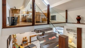 A modern interior with a glass staircase, wooden furniture, and a view of a bedroom.