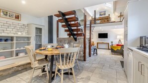 A modern kitchen with a dining area, a staircase, and a TV.