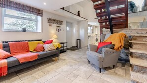 A modern living room with a sofa, armchair, and a staircase.
