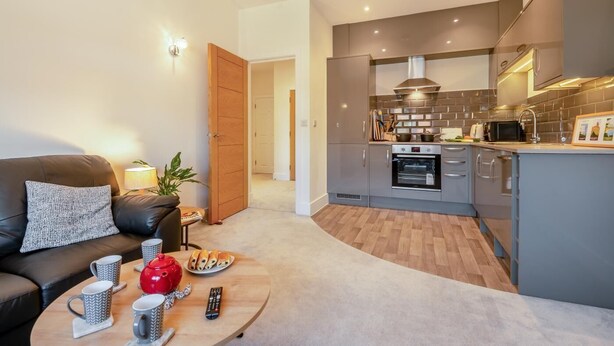 A modern apartment with a living room, kitchenette, and a door leading to another room. - 2 Bed in Swanage (oc-s31851) (Swanage)