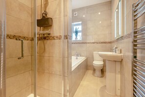 Uma casa de banho moderna com chuveiro envidraçado, banheira e sanita.