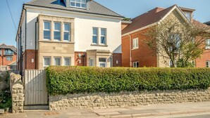 A two-story house with a stone facade, a visible garage door, and a well-maintained hedge. - 2 Bed in Swanage (oc-s31851) (Swanage)
