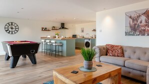 A modern living room with a pool table, a sofa, a coffee table, and a kitchen in the background. - 1 Bed in Badgeworth (oc-b31881) (Badgeworth)