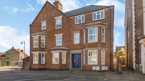 A two-story brick building with a bay window on the ground floor and a blue door. - 1 Bed in Sheringham (oc-n31825) (Sheringham)