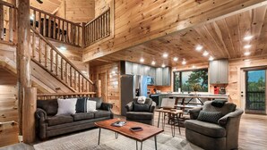 Un vaste espace de vie agrémenté d’un escalier en bois, une cuisine équipée d’appareils électroménagers modernes et un coin salon confortable.