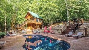 Une cabane en bois dotée d’une terrasse, entourée d’une piscine et de chaises longues.