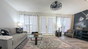 A living room with a sofa, a coffee table, a rug, and a television.