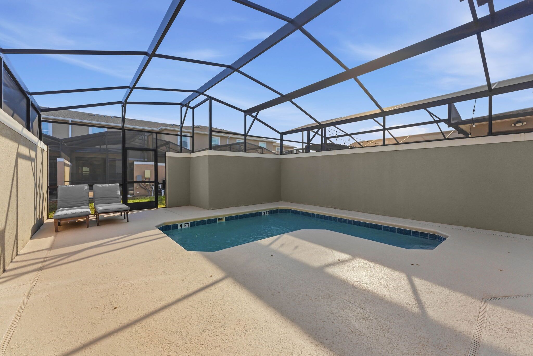 An indoor swimming pool with a glass ceiling, lounge chairs, and a clear view of the surrounding buildings.