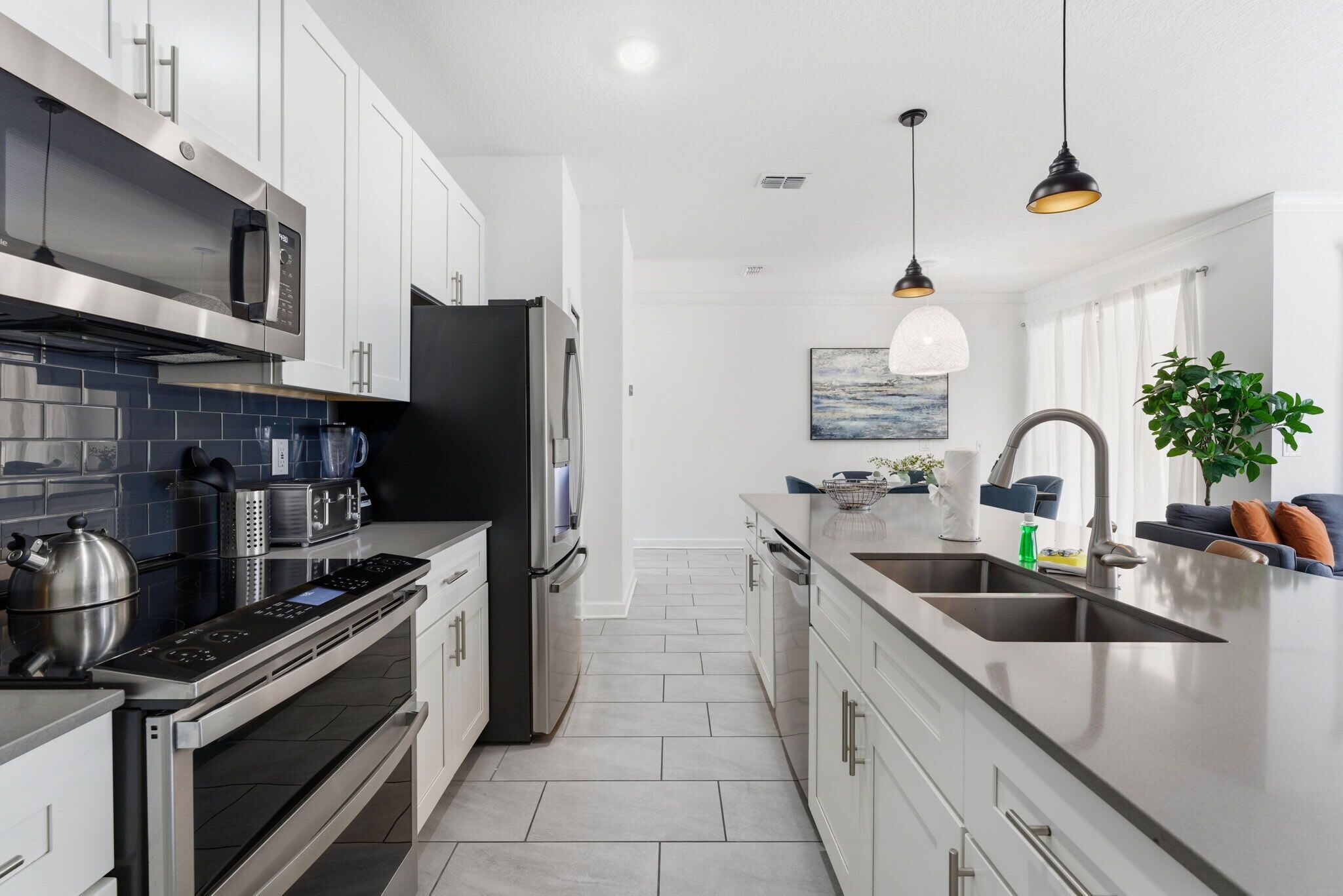 A modern kitchen with stainless steel appliances, a large island with a sink, and pendant lighting.