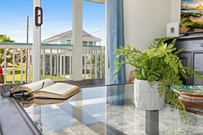 Ein Zimmer mit Glastisch, offenem Buch und einem Topf mit Farne.