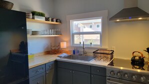 A kitchen with a sink, stove, and a window with a view of a building outside. - Charming 1-bedroom apartment. Walk everywhere! A perfect Bellingham getaway. (Bellingham)