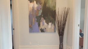 A hallway with a dark blue floor, a large abstract painting on the wall, and a tall vase with thin branches. - Charming 1-bedroom apartment. Walk everywhere! A perfect Bellingham getaway. (Bellingham)