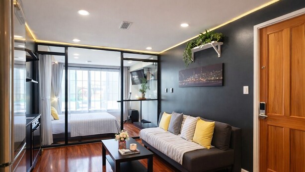 Una habitación de hotel moderna con sofá, una mesa de centro, un televisor y un cuadro de paisaje urbano.