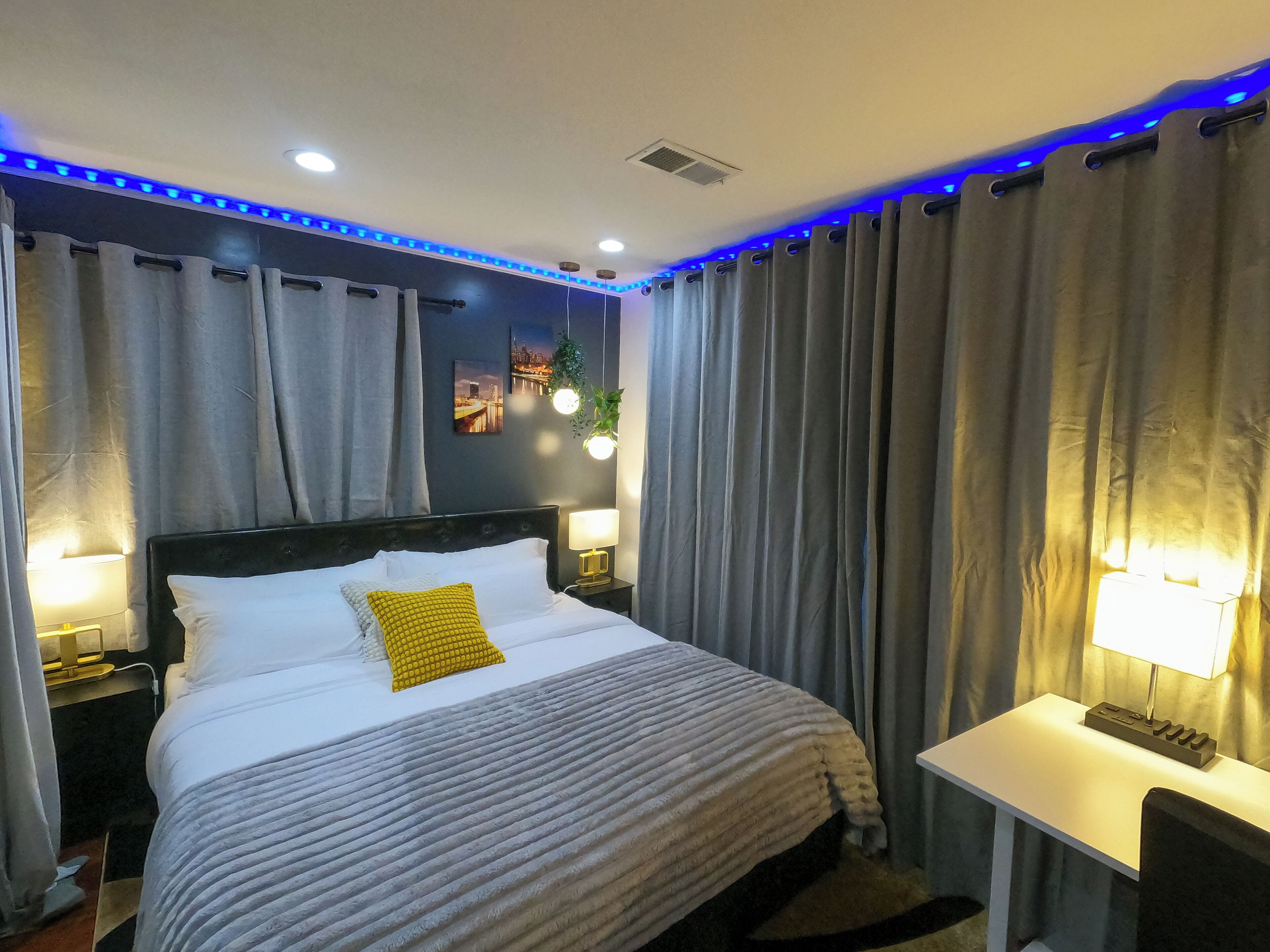 Una habitación de hotel moderna con una cama grande, dos lámparas de noche, una mesita pequeña y un escritorio.