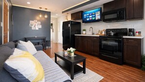 Una sala de estar moderna con sofá, mesa de centro y televisor sobre la encimera de la cocina.