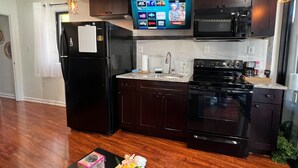 Una cocina moderna con armarios de madera oscura, un refrigerador negro, un microondas y una estufa.