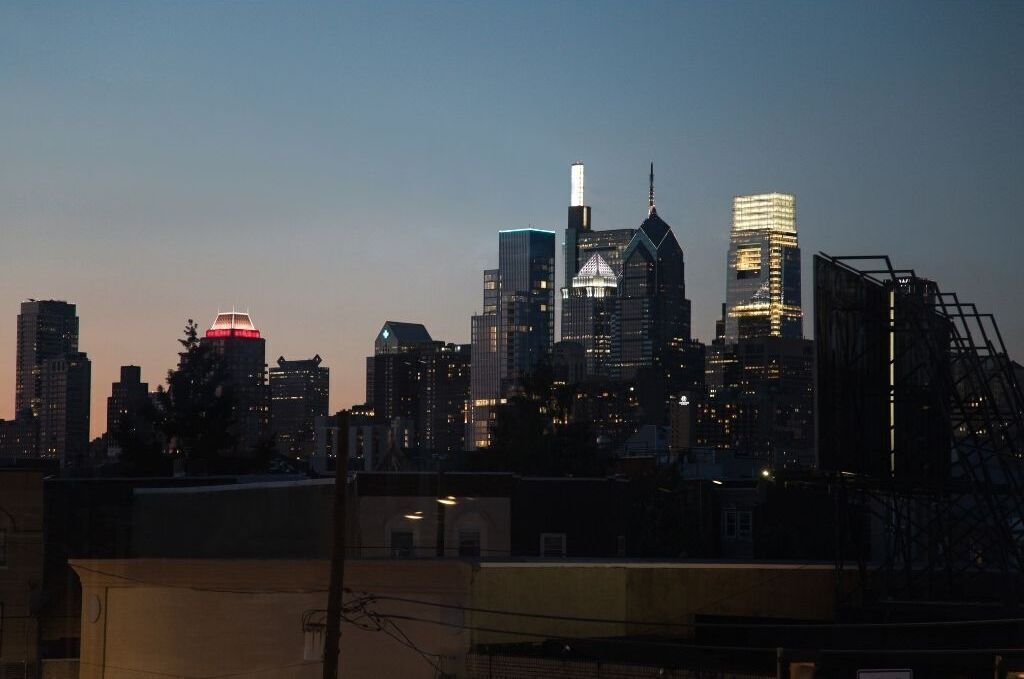 A city skyline at dusk with illuminated buildings and a prominent dome structure.