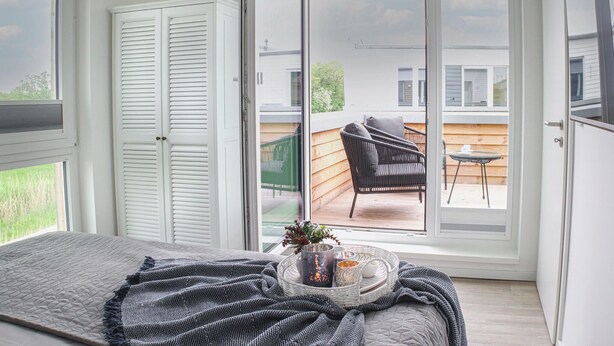 A bedroom with a large sliding glass door leading to an outdoor patio. - Lovely home in Butjadingen with sauna (Butjadingen)