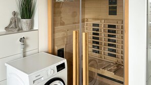 A modern laundry room with a Siemens washing machine, wooden shelves, and a glass door leading to a sauna area. - Lovely home in Butjadingen with sauna (Butjadingen)