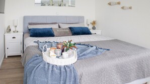 A neatly arranged bedroom with a bed, bedside tables, a wall-mounted picture, and decorative items. - Lovely home in Butjadingen with sauna (Butjadingen)