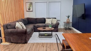 Una sala de estar moderna con un sofá modular, una mesa de centro y un televisor montado en la pared.
