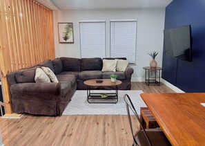 A modern living room with a sectional sofa, a coffee table, and a TV mounted on the wall. - Remodeled 3BR 2B • 15 min to OSU • Near Top Hospitals • Nightlife • Quiet Area (Powell)
