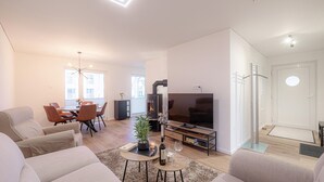 Een moderne woonkamer met een bank, televisie en een open haard.