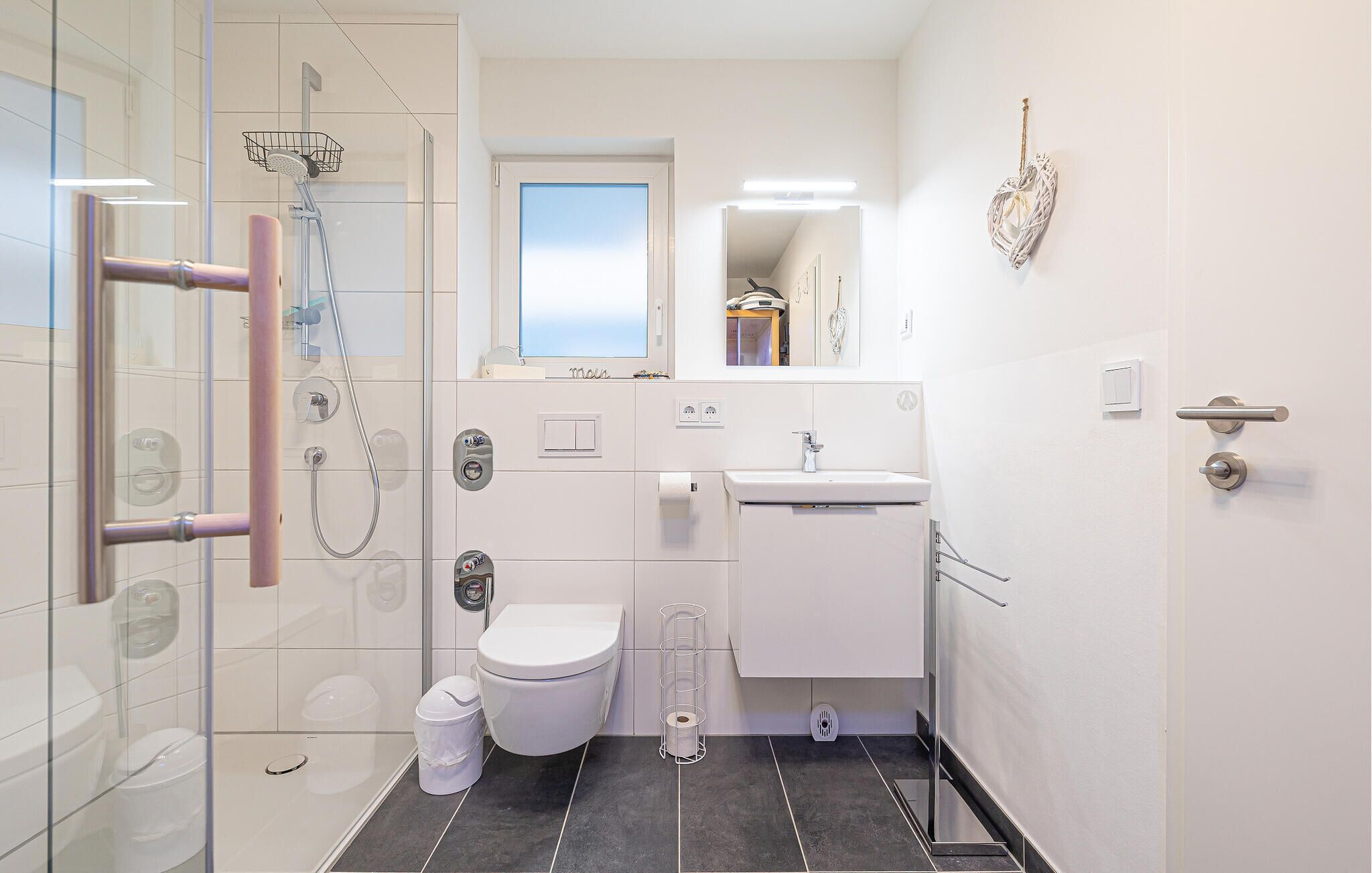Un baño moderno con cabina de ducha de vidrio, inodoro, lavabo y espejo.
