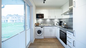 Een moderne keuken met een wasmachine, oven en magnetron.
