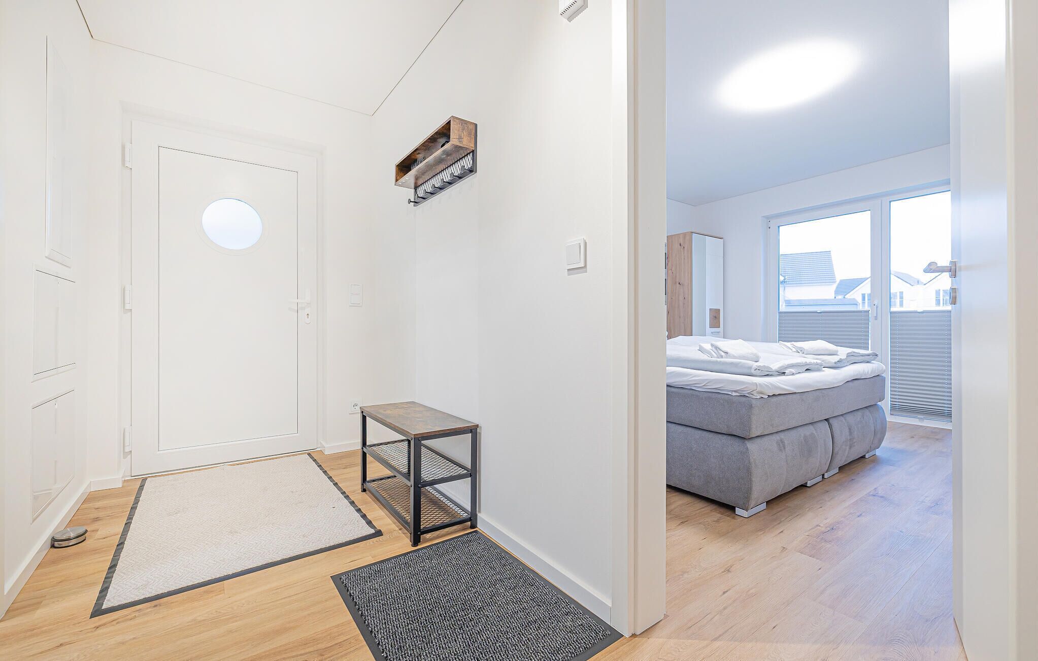 A modern apartment with a large bed, a small table, and a view of the outside through a large window.