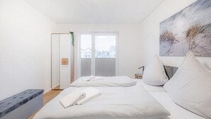 Een moderne slaapkamer met een groot bed, een bankje en een schilderij.