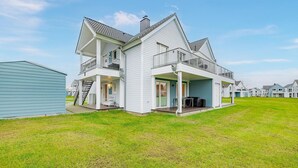 Een huis met twee verdiepingen, een balkon, een overdekte veranda en een trap naar de bovenverdieping.