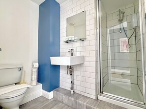 Ein Badezimmer mit Toilette, Waschbecken und einer Duschkabine aus Glas.