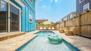A backyard with a swimming pool, lounge chairs, and a wooden fence. - Family Beach Escape w/ Private Pool|Downtown St. A (St. Augustine)