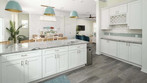 A spacious kitchen with white cabinets, a large island, and teal pendant lighting. - Family Beach Escape w/ Private Pool|Downtown St. A (St. Augustine)