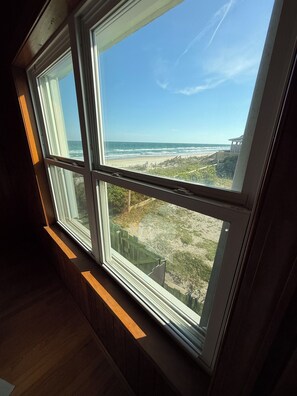 Ein Zimmer mit großem Fenster und Blick auf einen Strand.