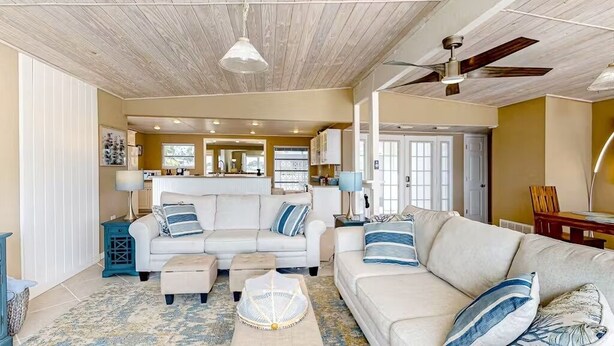 A spacious living room with a large white sofa set, a coffee table, and a ceiling fan. - Morgan Lake House: Clean and Open Floorplan with Stunning Views (Port Charlotte)