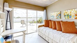 A bedroom with a sofa bed, a desk, and a chair. There is a large window with a view of a body of water. - Morgan Lake House: Clean and Open Floorplan with Stunning Views (Port Charlotte)