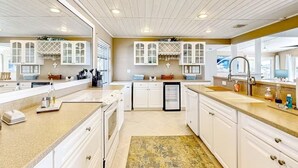 A modern kitchen with white cabinets, a central island, and a large window. - Morgan Lake House: Clean and Open Floorplan with Stunning Views (Port Charlotte)