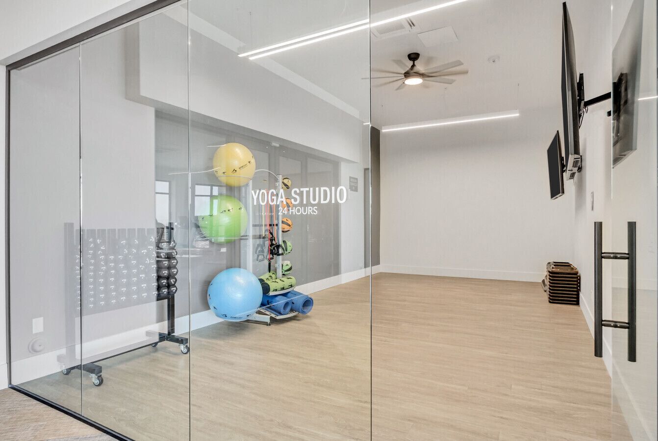 Un studio de yoga doté d’un mur en verre, de tapis de yoga et de ballons d’exercice.