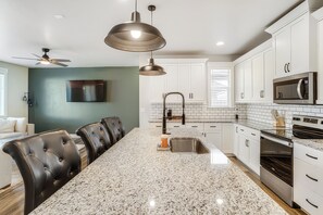 A modern kitchen with a granite countertop, stainless steel appliances, and a dining area with leather chairs. - The Meadows Nook- a comfy, cozy, modern home in the heart of Middleton Idaho (Middleton)