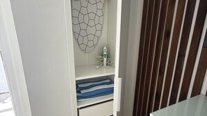 Un closet amplio con un perchero, una toalla doblada y una plancha pequeña.