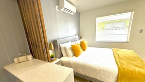 Una habitación de hotel moderna con cama, mesita de noche y ventana con persianas.