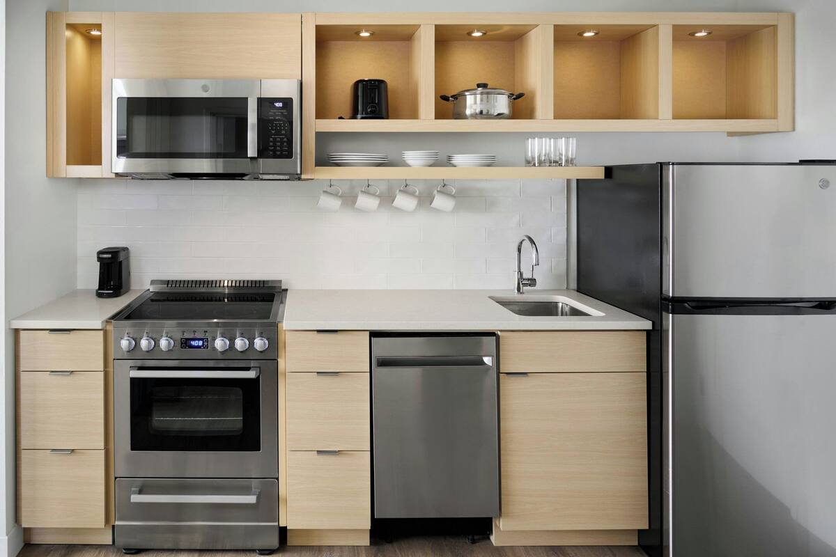 A modern kitchen with stainless steel appliances, wooden cabinets, and a built-in dishwasher.