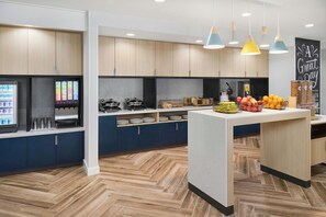 A modern kitchen with wooden cabinets, a central island, and a beverage dispenser. - Towneplace Suites By Marriott Romeoville (Romeoville)