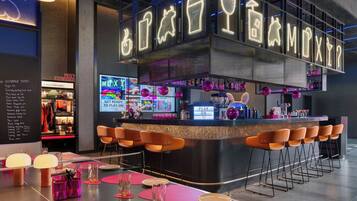 A bar area with neon signs, bar stools, and a counter.