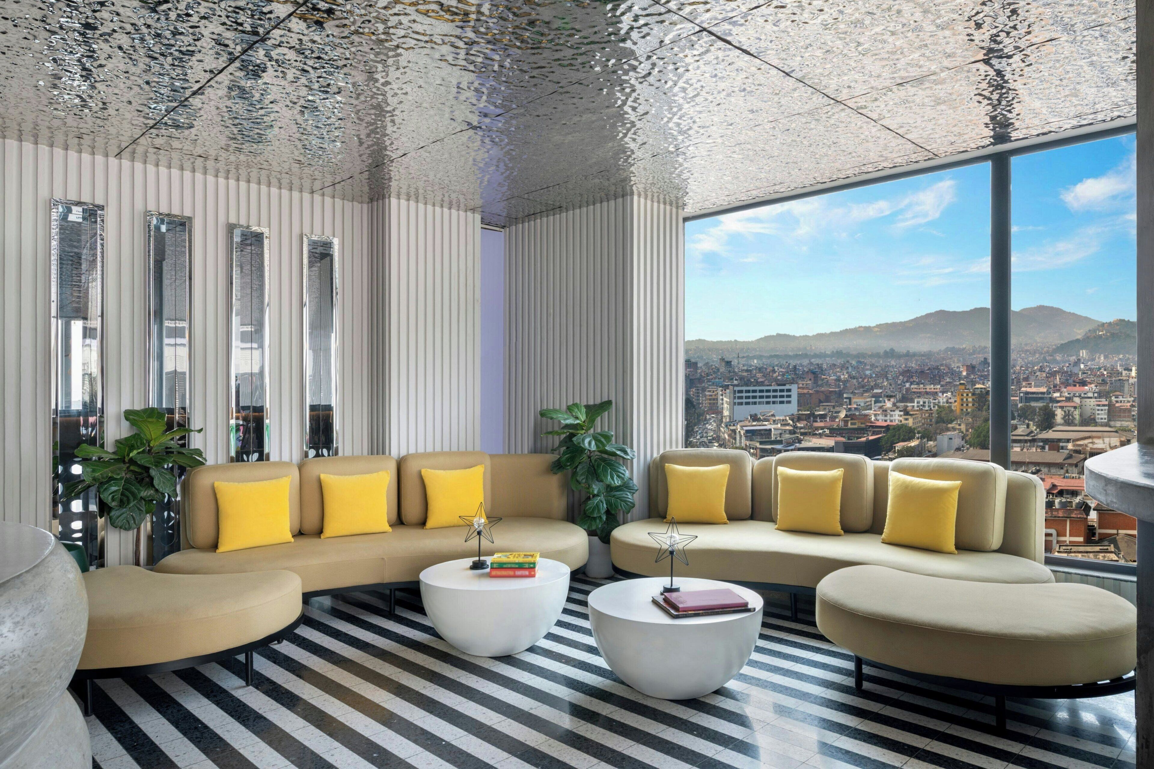 Ein modernes Wohnzimmer mit einer Sofagarnitur, zwei Couchtischen und großen Fenstern mit Blick auf die Stadt.